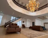 نمایی از سالن نشیمن با دیوار سفید پله و نرده های چوبی قهوه ای چوبی و لوستر بلند ویلا در قائمشهر 523451345